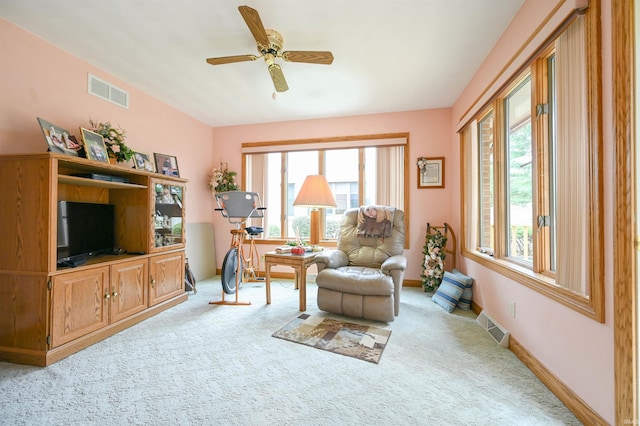 living area featuring a wealth of natural light, ceiling fan, and light carpet