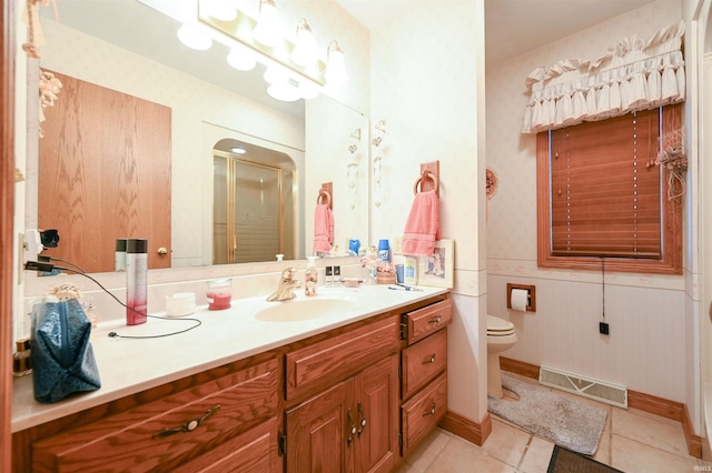 bathroom featuring tile patterned flooring, vanity, a shower with door, and toilet