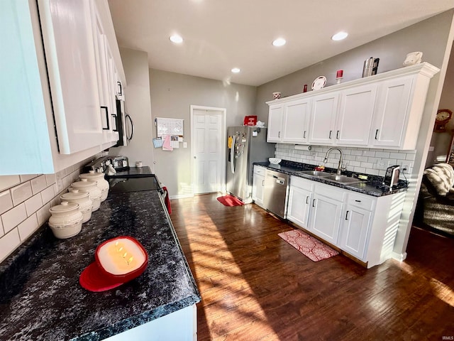 kitchen featuring dark wood-type flooring, white cabinets, sink, appliances with stainless steel finishes, and dark stone countertops