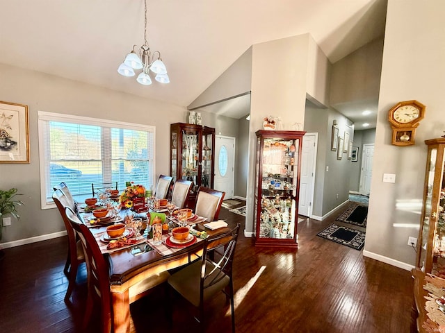 dining room with dark wood-type flooring, a chandelier, and high vaulted ceiling