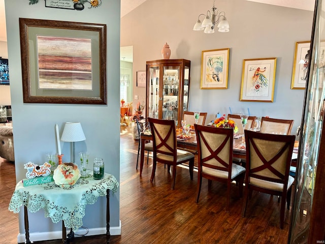 dining space with hardwood / wood-style floors, a chandelier, and vaulted ceiling