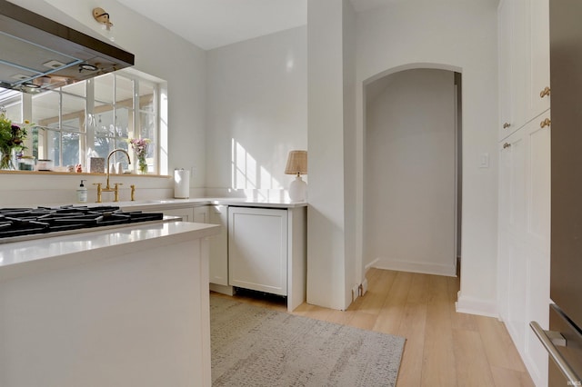 kitchen featuring white cabinets, gas stovetop, light wood-type flooring, and extractor fan