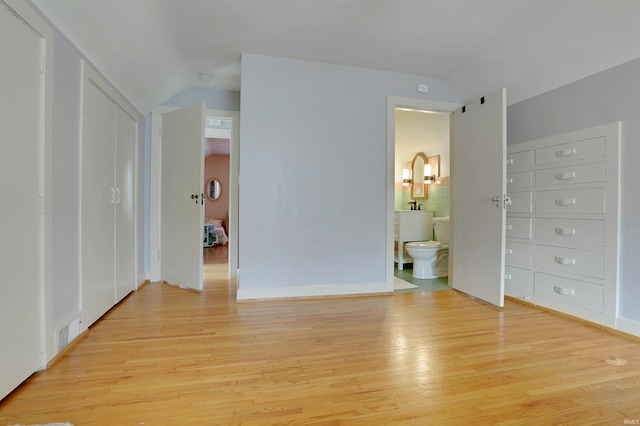 unfurnished bedroom with ensuite bathroom and light wood-type flooring