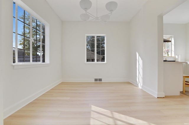 unfurnished dining area with a wealth of natural light, light hardwood / wood-style floors, and a notable chandelier