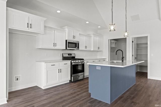 kitchen with stainless steel appliances, white cabinetry, hanging light fixtures, an island with sink, and lofted ceiling