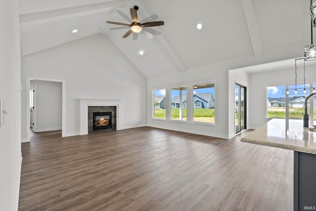 unfurnished living room featuring dark wood-type flooring, a fireplace, high vaulted ceiling, and beam ceiling