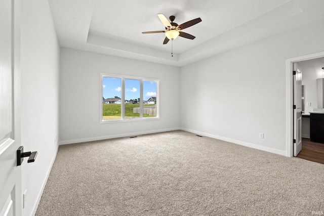 unfurnished room with ceiling fan, carpet floors, and a tray ceiling