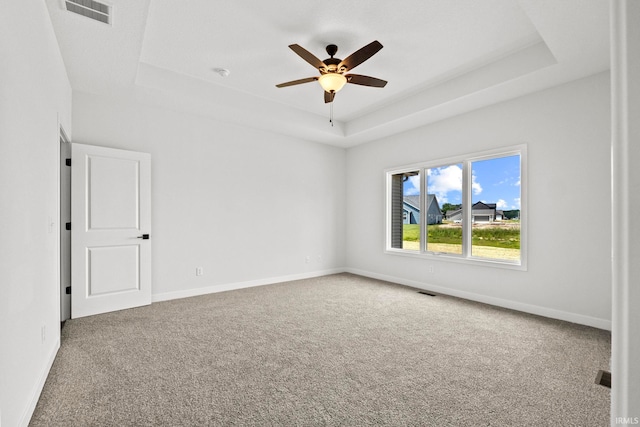 spare room featuring ceiling fan, carpet floors, and a raised ceiling