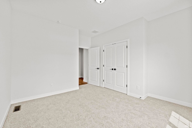 unfurnished bedroom with light colored carpet and a closet