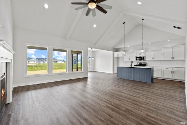 unfurnished living room with high vaulted ceiling, dark hardwood / wood-style floors, ceiling fan, and beam ceiling