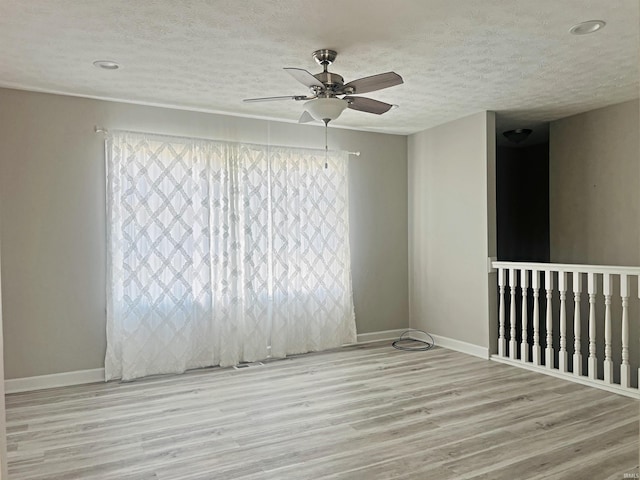 unfurnished room with ceiling fan, a textured ceiling, and light hardwood / wood-style floors