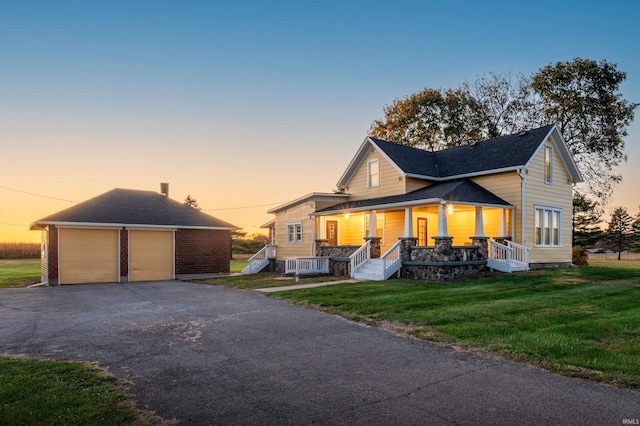 view of front of home featuring a lawn, a garage, an outdoor structure, and a porch