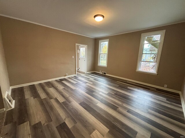 empty room with visible vents, baseboards, ornamental molding, and dark wood finished floors