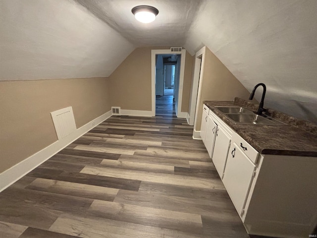 interior space with white cabinetry, dark hardwood / wood-style flooring, lofted ceiling, and sink