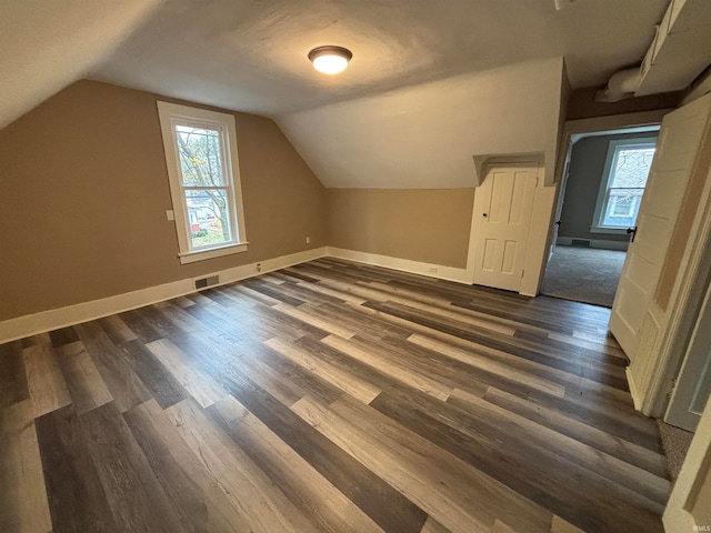 bonus room with dark wood-type flooring and lofted ceiling