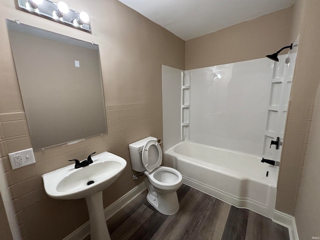 bathroom featuring toilet, tile walls, hardwood / wood-style floors, and shower / bathtub combination