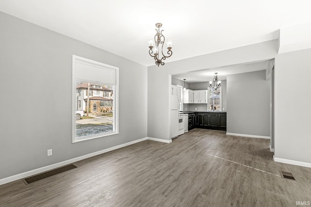 unfurnished living room featuring hardwood / wood-style flooring and an inviting chandelier