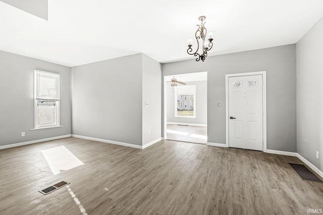 unfurnished room featuring ceiling fan with notable chandelier and light hardwood / wood-style floors