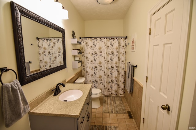 bathroom featuring walk in shower, tile patterned flooring, a textured ceiling, vanity, and toilet