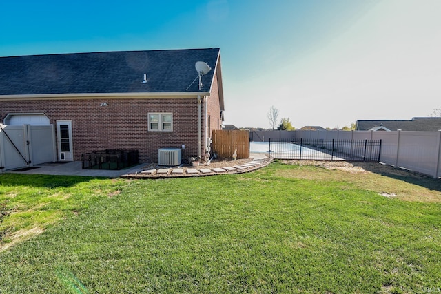 rear view of house with a lawn, central AC, and a patio area