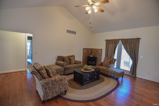 living room with high vaulted ceiling, ceiling fan, a wood stove, and dark hardwood / wood-style floors