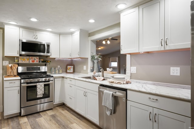 kitchen with light wood-type flooring, appliances with stainless steel finishes, and white cabinets