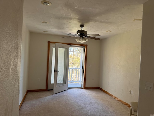 spare room with ceiling fan and light carpet