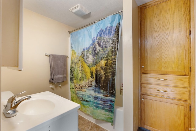 bathroom featuring tile patterned floors, vanity, shower / bath combination with curtain, and a textured ceiling