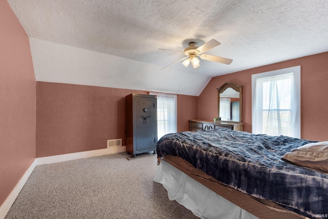 bedroom with a textured ceiling, carpet floors, vaulted ceiling, and ceiling fan