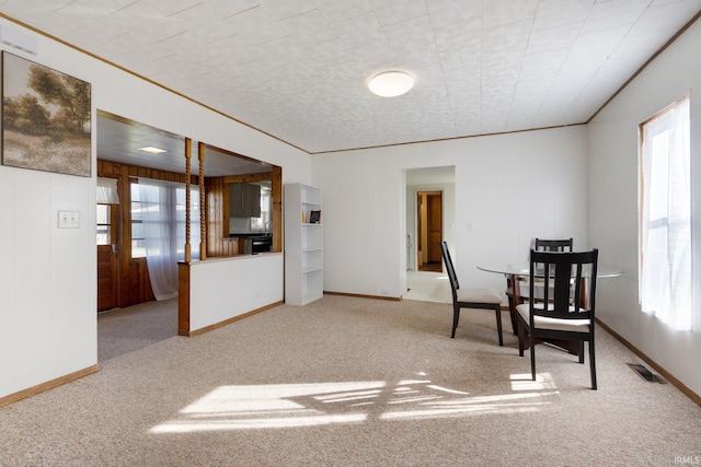 dining room with crown molding, plenty of natural light, and carpet