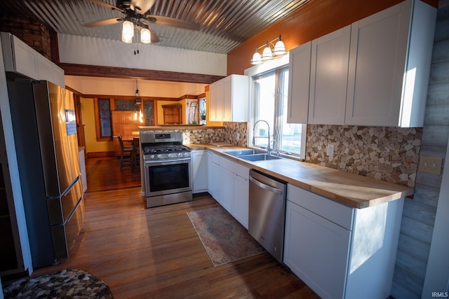 kitchen with pendant lighting, white cabinets, sink, dark hardwood / wood-style floors, and stainless steel appliances