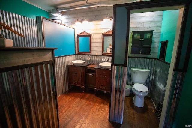 bathroom featuring wooden walls, hardwood / wood-style floors, vanity, and toilet