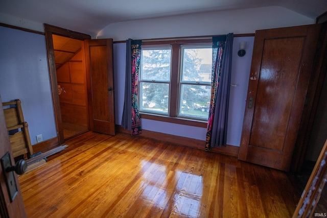 unfurnished bedroom with lofted ceiling and light hardwood / wood-style flooring