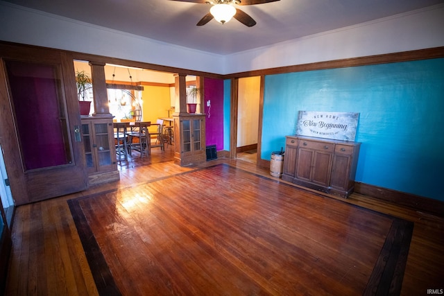 unfurnished room with decorative columns, hardwood / wood-style flooring, ornamental molding, and ceiling fan