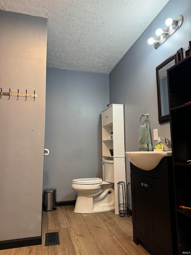 bathroom featuring toilet, vanity, a textured ceiling, and hardwood / wood-style flooring