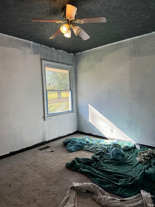 unfurnished bedroom with ceiling fan, carpet, and a textured ceiling