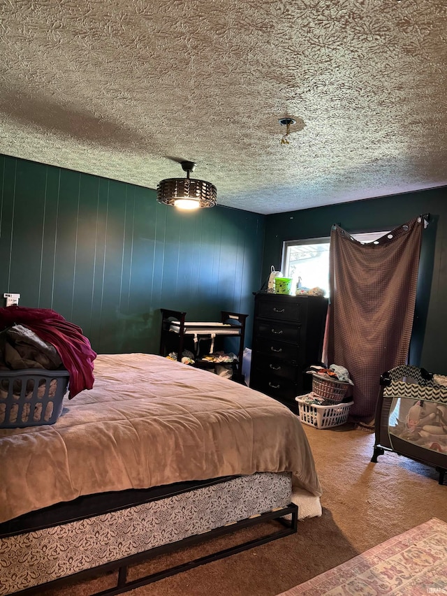 bedroom featuring carpet flooring, wooden walls, and a textured ceiling