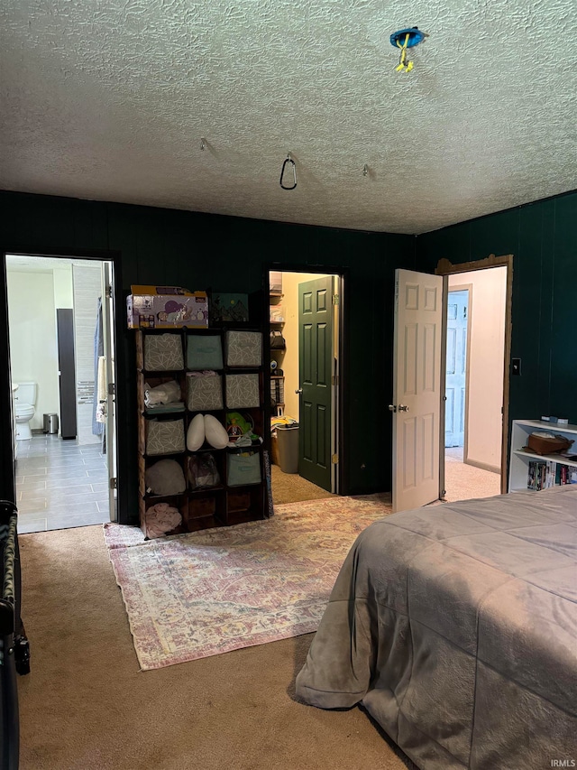 carpeted bedroom with ensuite bathroom and a textured ceiling