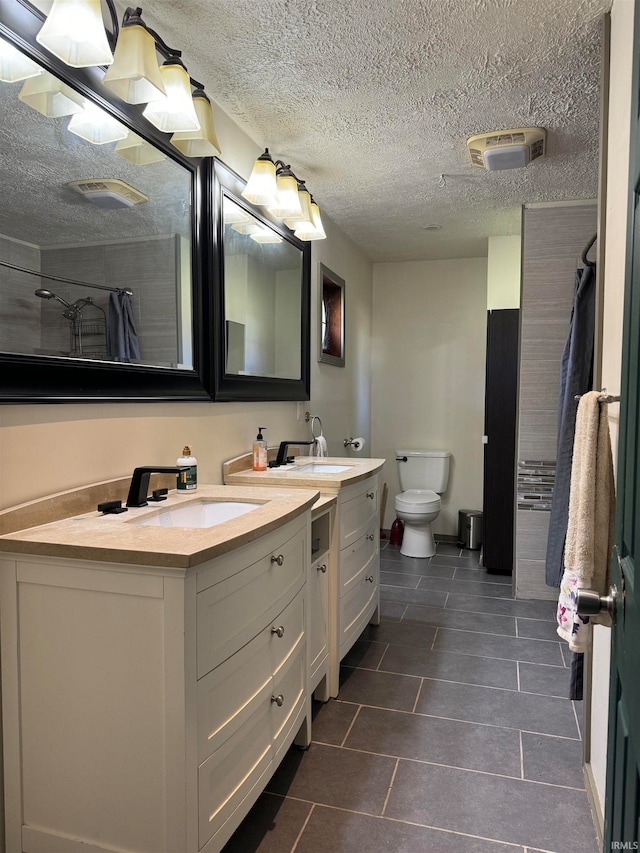 bathroom with tile patterned floors, vanity, a textured ceiling, and toilet