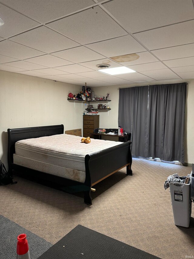 bedroom featuring a drop ceiling and carpet