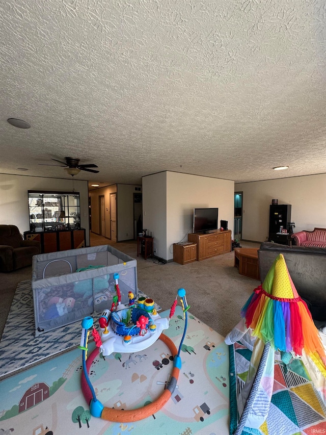 living room featuring ceiling fan, carpet, and a textured ceiling