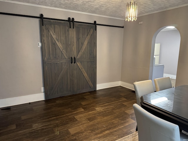 dining space featuring dark hardwood / wood-style flooring, a barn door, a textured ceiling, and ornamental molding