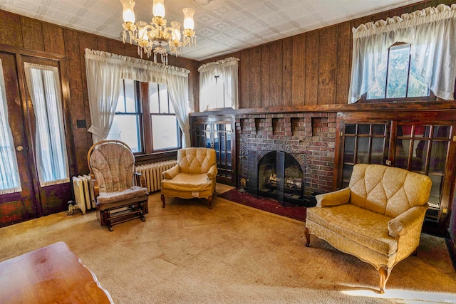 sitting room with a fireplace, radiator, wooden walls, and carpet flooring