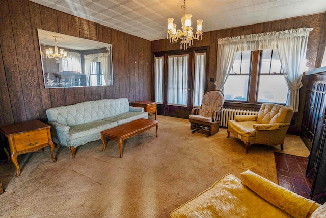 carpeted living room featuring radiator heating unit, a healthy amount of sunlight, and an inviting chandelier