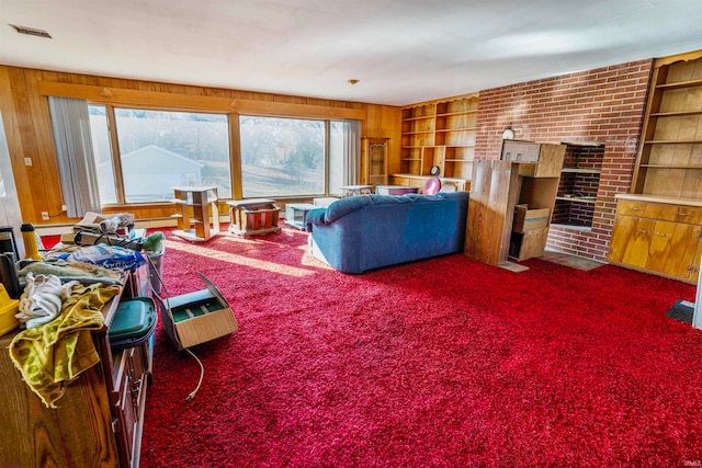 carpeted living room with built in features, wood walls, and a wealth of natural light