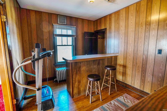 bar featuring radiator heating unit, wood walls, and dark hardwood / wood-style flooring