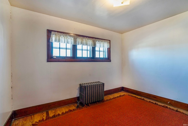 empty room with radiator and hardwood / wood-style flooring