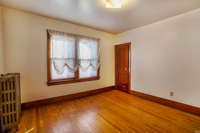 spare room with radiator heating unit and light hardwood / wood-style flooring