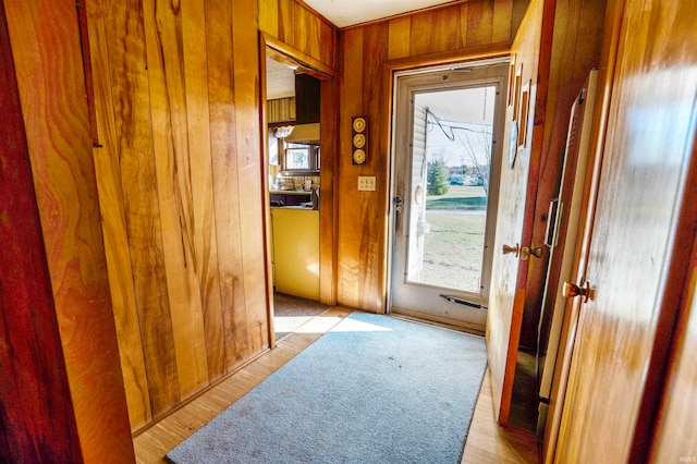 hall with wood walls, a wealth of natural light, and light hardwood / wood-style flooring