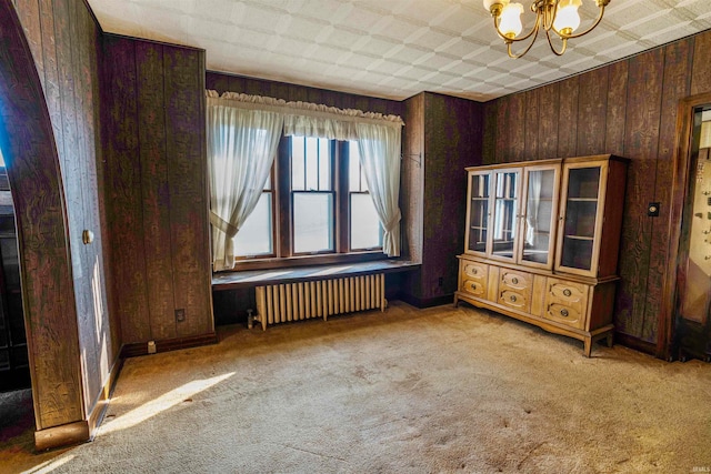 interior space featuring wood walls, a chandelier, and radiator